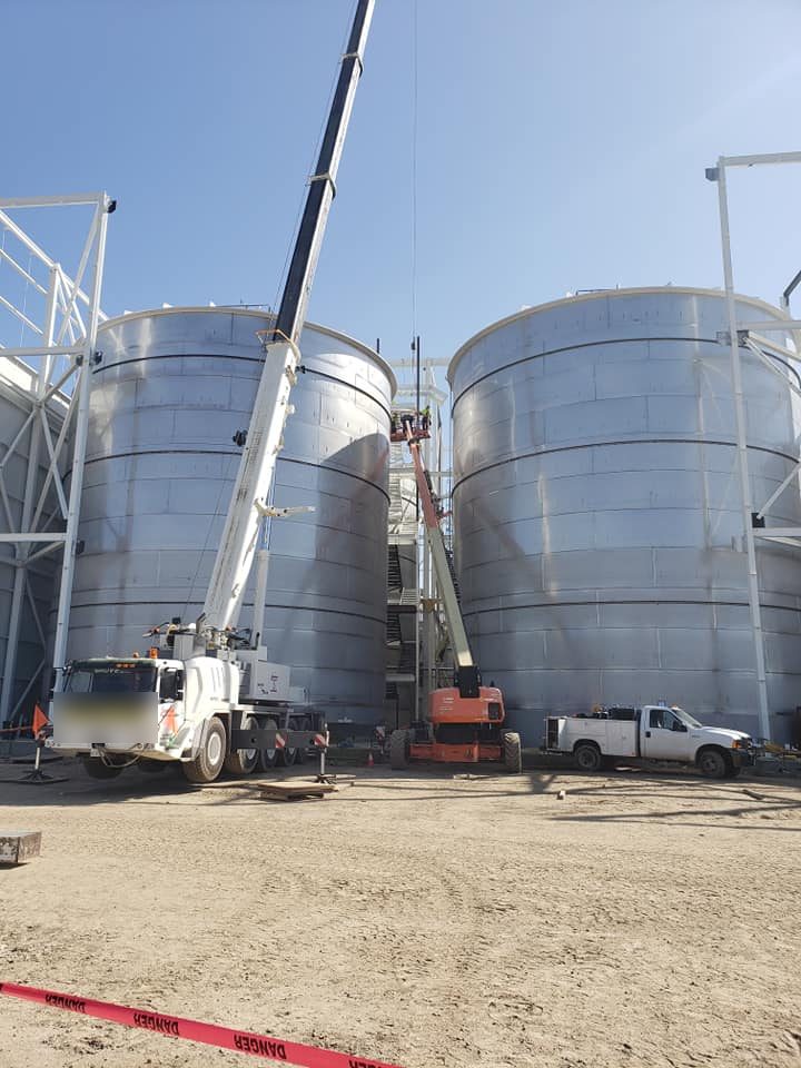 Crane and lift beside two large stainless tanks inside the support steel